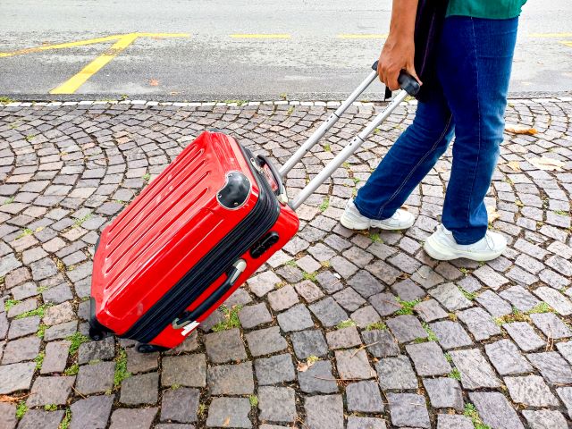 Frau mit Rollkoffer auf unebenem Untergrund